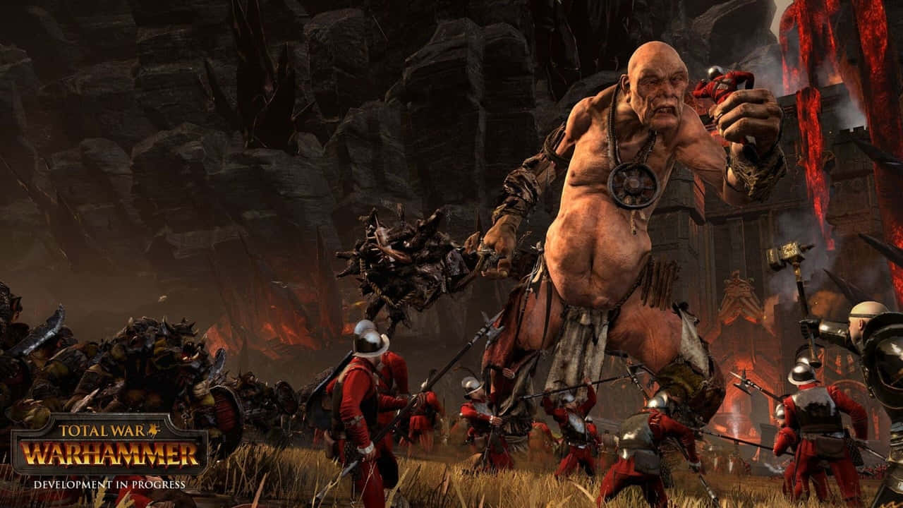 Total War Warhammer 2 桌布 壁紙 — 一個巨大、肌肉發達的獸人 warlord 揮舞著帶刺的棍棒，他身穿紅色衣服的士兵軍隊衝過熾熱的火山戰場。