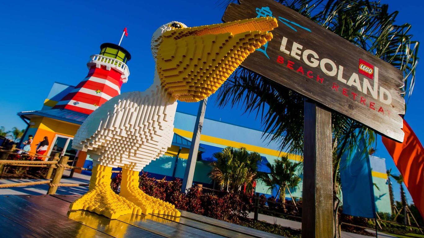 樂高 桌布 壁紙 — 一個巨大的LEGO鵜鶘雕像在LEGOLAND Beach Retreat驕傲地矗立，背景是晴朗的藍天和條紋燈塔。