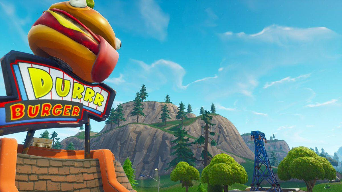 Fortnite 縮圖 桌布 壁紙 — 一個巨大的卡通漢堡棲息在 Durrr Burger 的彩色招牌上，背景是明亮的藍天、岩石山丘和樹木。