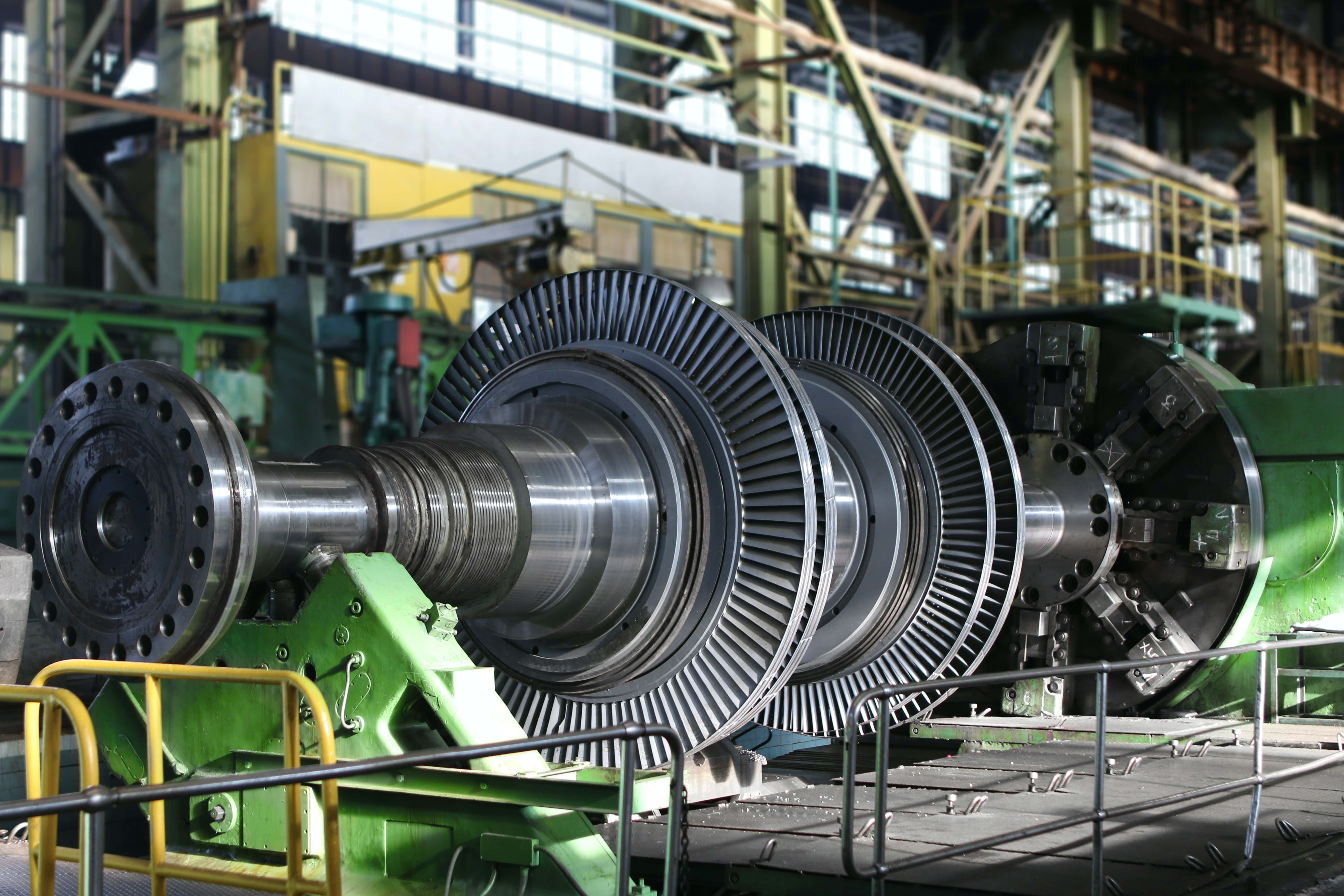 Mechanical Engineering 桌布 壁紙 — 一個巨大的工業渦輪轉子放置在鋼結構工廠大廳內的綠色機械上。