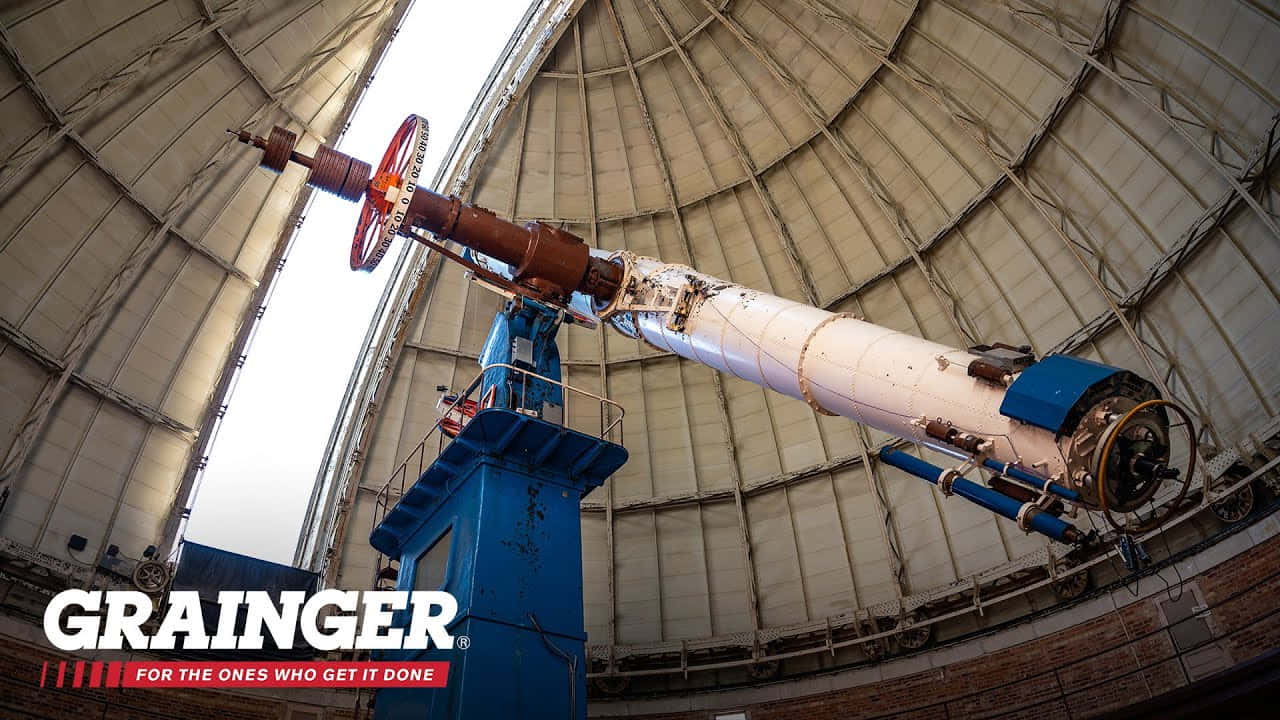 Observatory 桌布 壁紙 — 一個巨大的復古望遠鏡主導著圓頂天文台的內部，帶有工業金屬結構和亮藍色支撐結構。