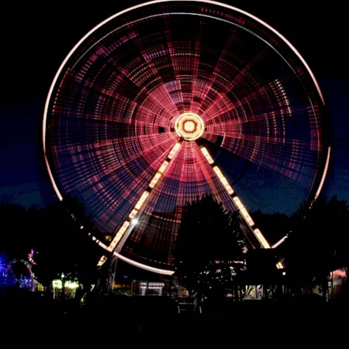 Dark Carnival 桌布 壁紙 — 一個巨大的摩天輪在漆黑的夜空下閃爍著鮮豔的紅白燈光，下方有樹木的剪影。