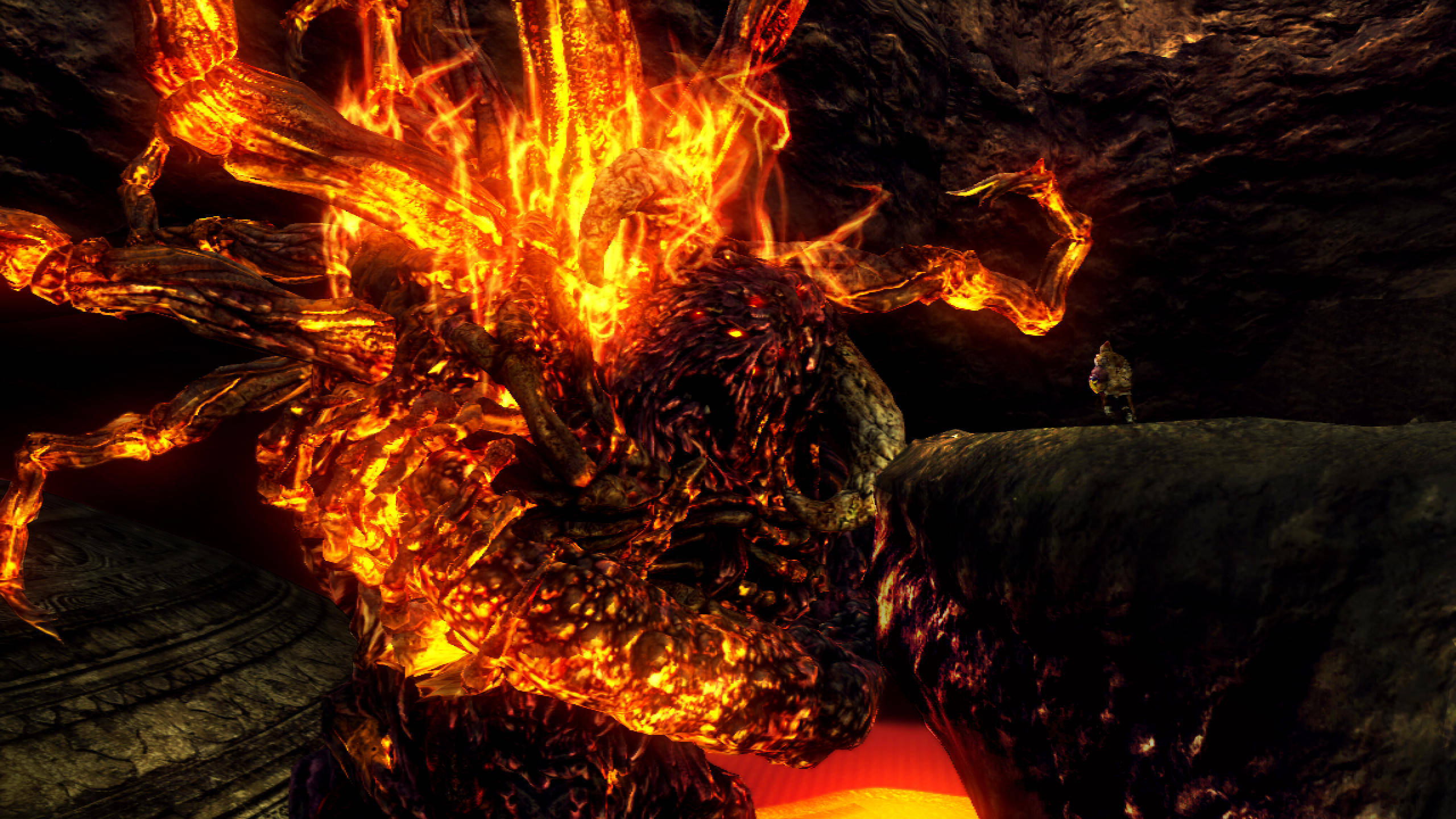 dark souls 4K 桌布 壁紙 — 一個巨大的熔岩怪物在黑暗的洞穴中爆發，附近有一個人影站在岩石上。