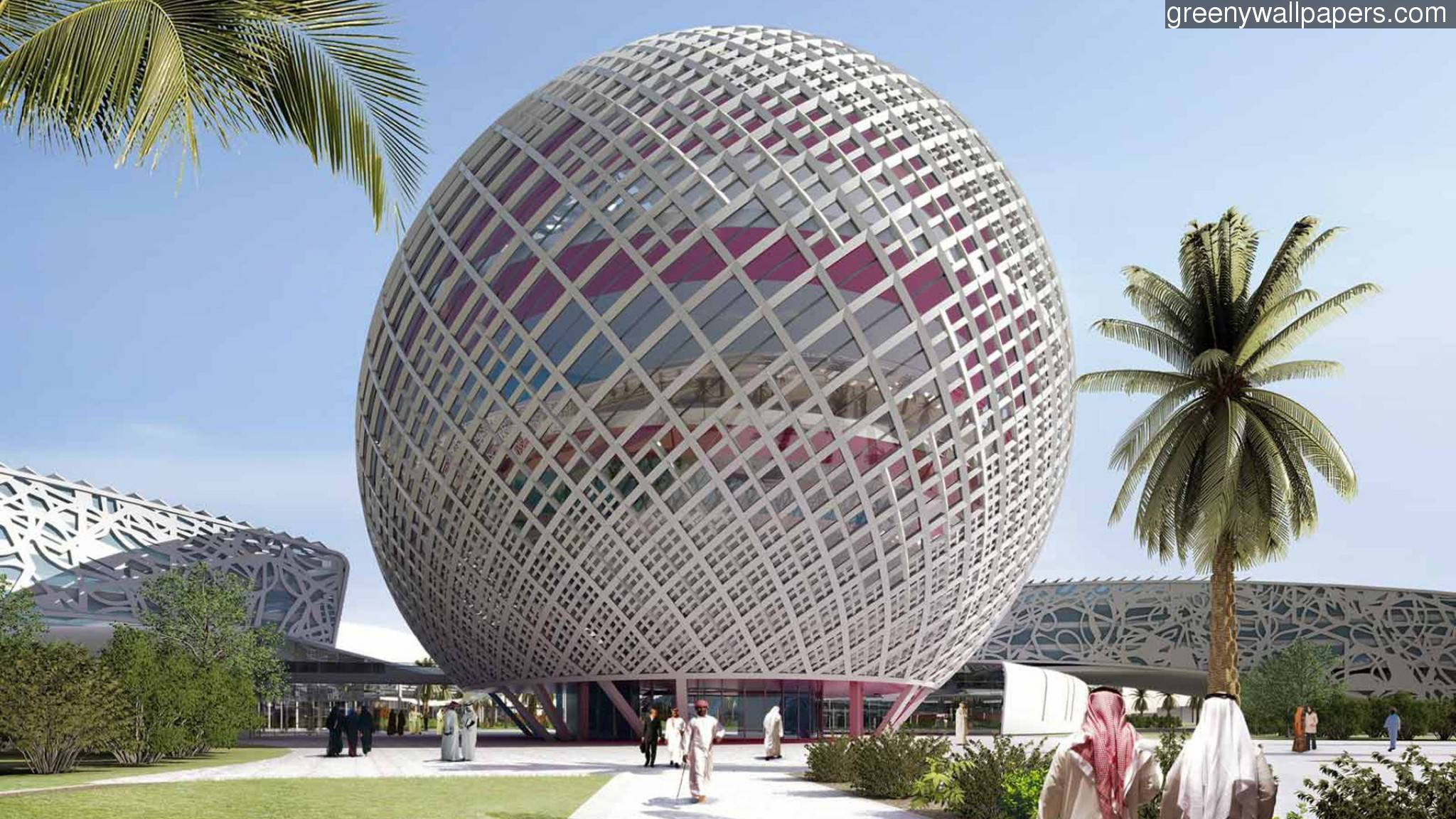 Bahrain 桌布 壁紙 — 一個巨大的球形網格結構，帶有粉紅色內部面板，矗立在晴朗的藍天下，兩旁是棕櫚樹和穿著傳統服飾的人們。