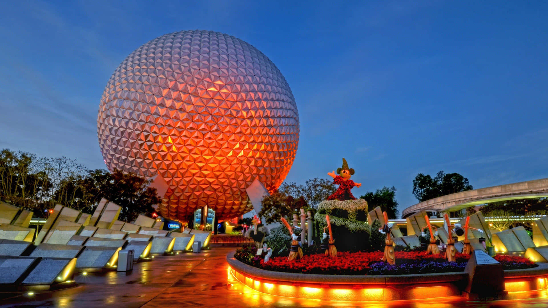 Disney World Desktop 桌布 壁紙 — 一個巨大的發光測地線球體在暮色天空中溫暖地發光，下方是節日花卉展示。
