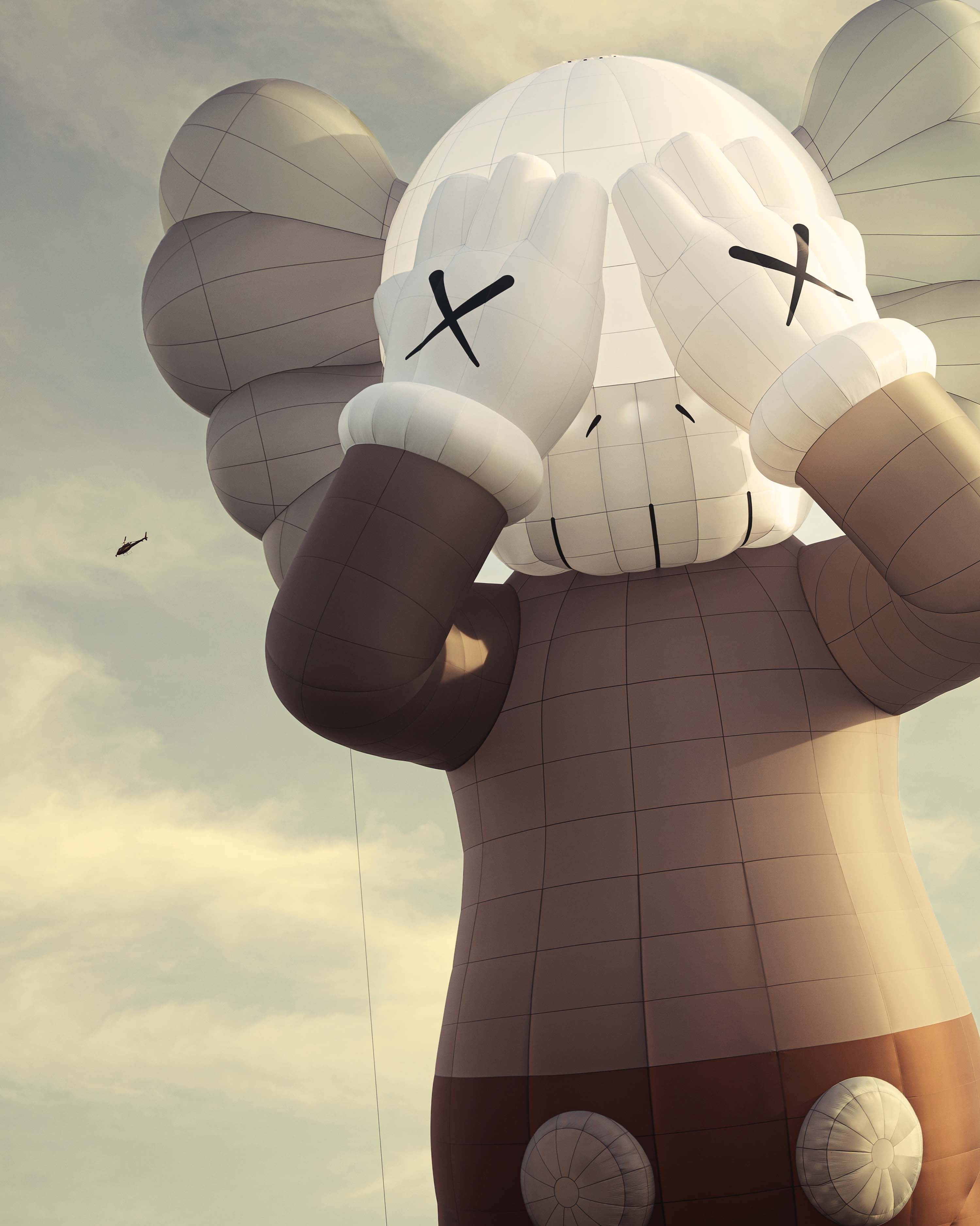 KAWS 桌布 壁紙 — 一個巨大的白色氣球雕塑，描繪KAWS角色，擁有X形眼睛並用手遮住臉龐，背景為多雲的天空。