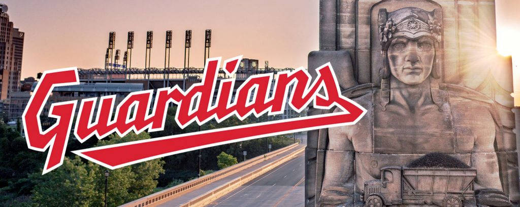 Cleveland Guardians 桌布 壁紙 — 一個巨大的石頭士兵雕像手持卡車，矗立在高速公路旁，背景有體育館和「Guardians」標誌，在夕陽餘暉中。