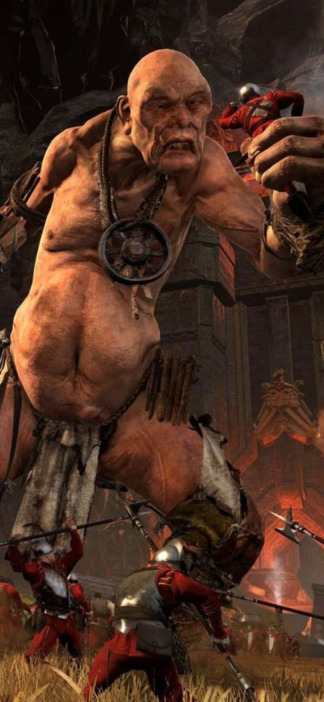 iPhone X Total War Warhammer 桌布 壁紙 — 一個巨大的禿頭食人魔，戴著尖刺項圈和部落纏腰布，在熾熱的戰場上揮舞著巨大的武器咆哮。