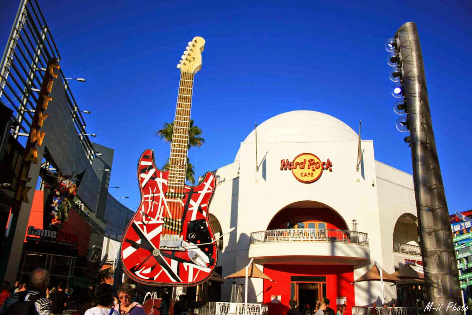 Universal 桌布 壁紙 — 一個巨大的紅白電吉他雕塑聳立在Hard Rock Cafe之上，在晴朗的藍天下，下方聚集了人群。