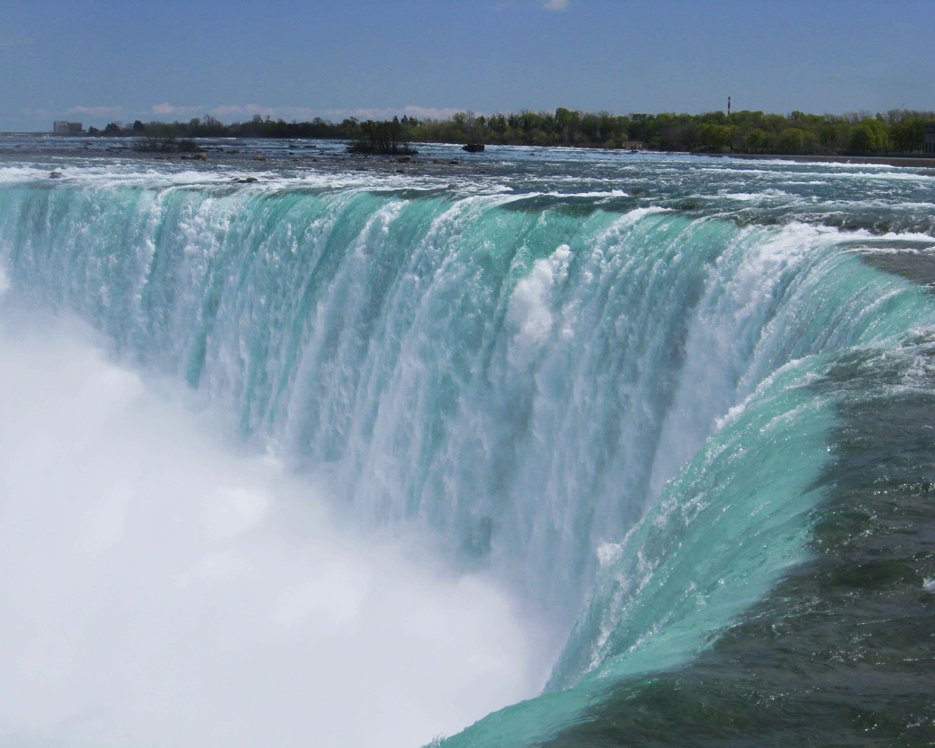 720p Niagara Falls 桌布 壁紙 — 一個巨大的藍綠色瀑布轟然落下，在晴朗的藍天下形成霧狀水花。