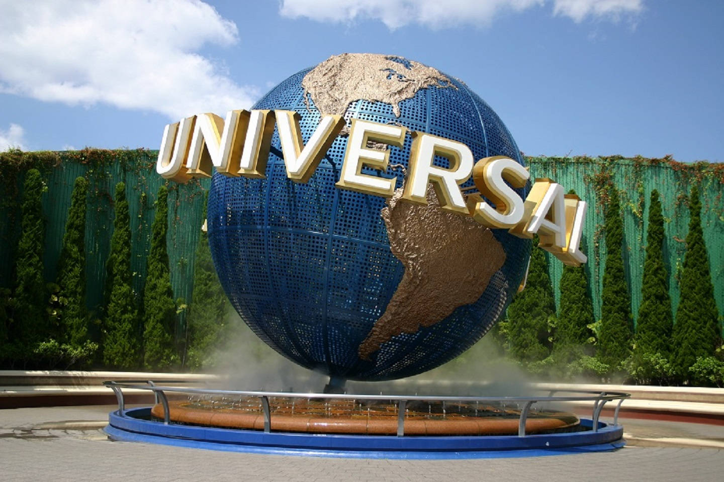 Universal 桌布 壁紙 — 一個巨大的藍色地球儀，上面有金色的「UNIVERSAL」字母，拱形跨越噴泉，背景是晴朗的藍天和蓬鬆的白雲。
