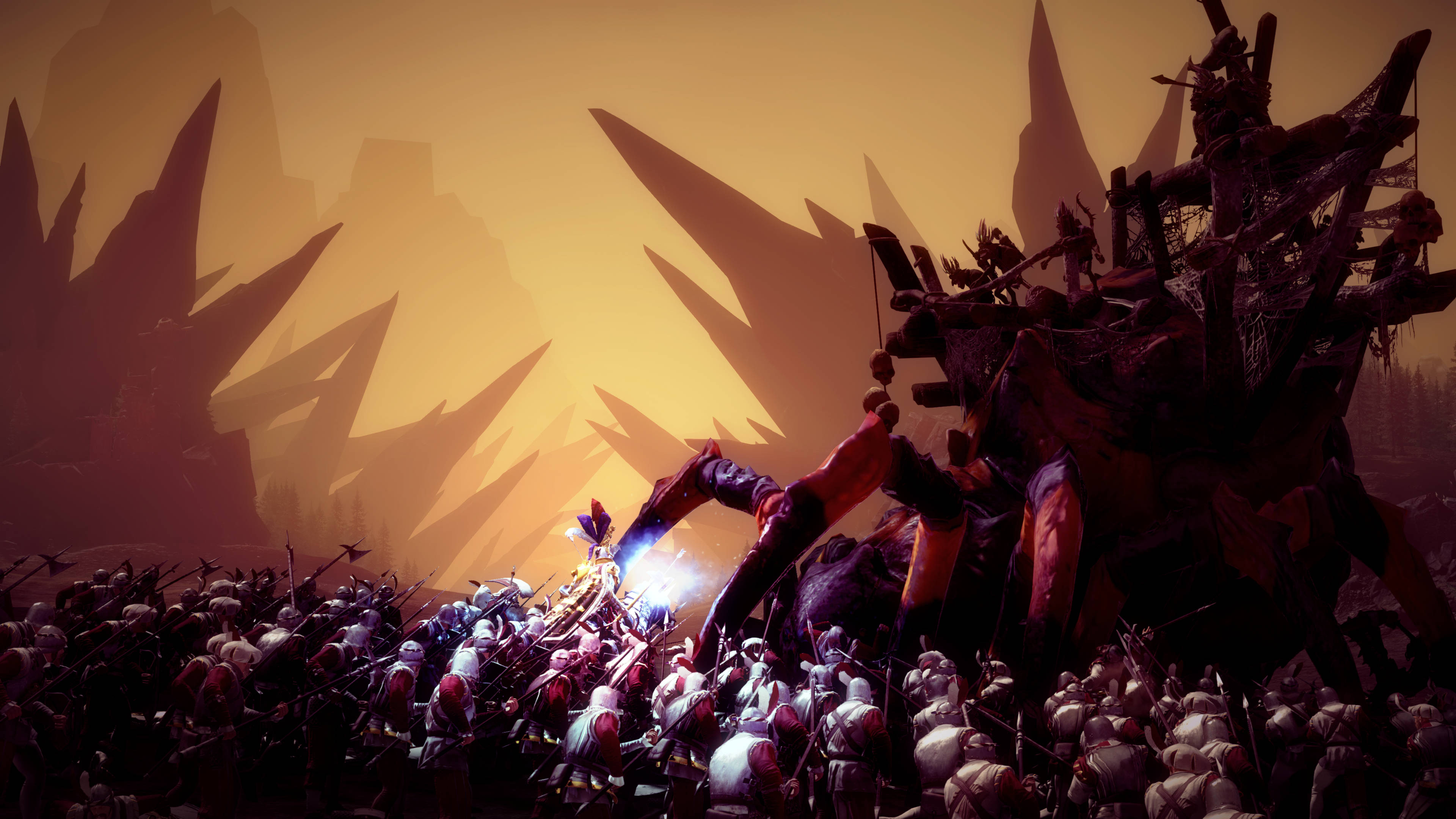 Total War Warhammer 2 桌布 壁紙 — 一個巨大的裝甲生物在發光的橙色天空下，背景有鋸齒狀的山脈，與一群士兵戰鬥。