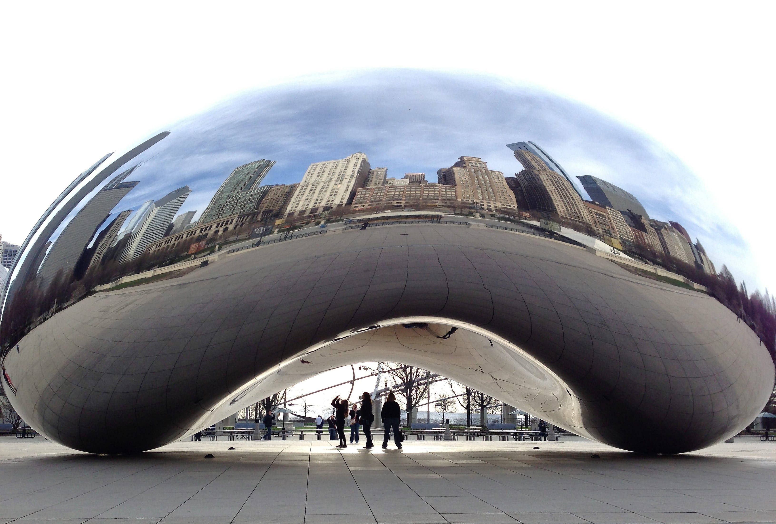 Sunny Day 桌布 壁紙 — 一個巨大的豆形鉻合金雕塑反射城市天際線，人們站在其彎曲拱門下。