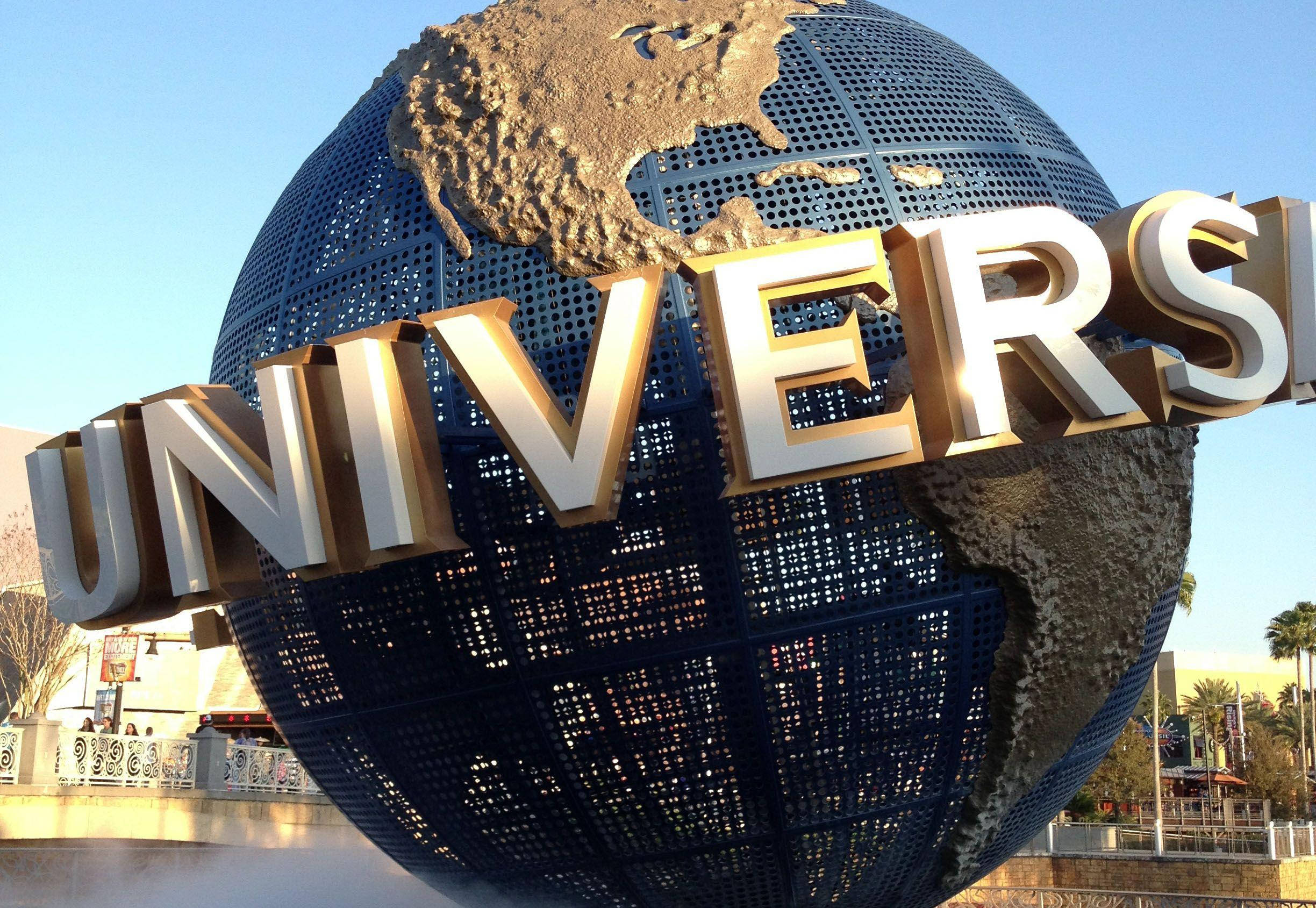 Universal 桌布 壁紙 — 一個巨大的金屬地球儀，上面有浮雕的大陸，前面有「UNIVERSAL」字樣，在晴朗的藍天下。