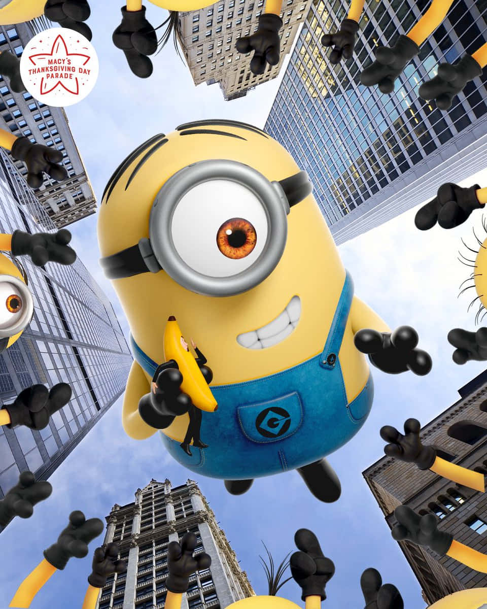 小小兵 桌布 壁紙 — 一個巨大的黃色Minion漂浮在摩天大樓上方，拿著一根香蕉，其他Minion從下方伸手。
