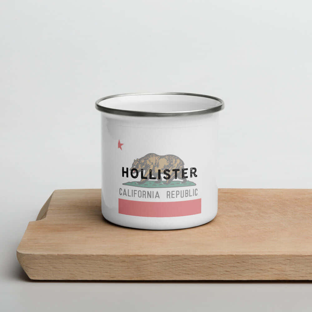 hollister 桌布 壁紙 — 一個帶有 Hollister California Republic 標誌的白色琺瑯杯，放在淺色木砧板中央，背景為純白色。