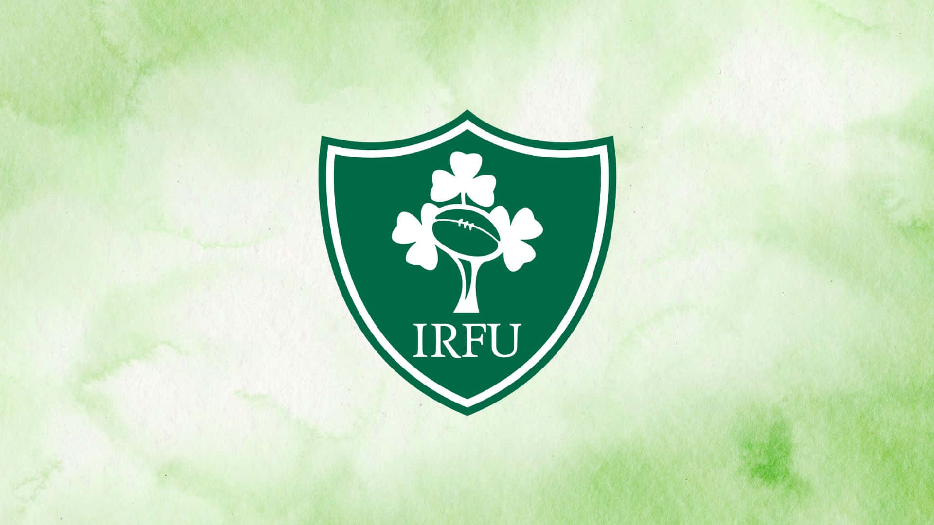 Ireland Rugby 桌布 壁紙 — 一個帶有三葉草和橄欖球的綠色盾牌標誌，居中放在水彩綠色背景上。