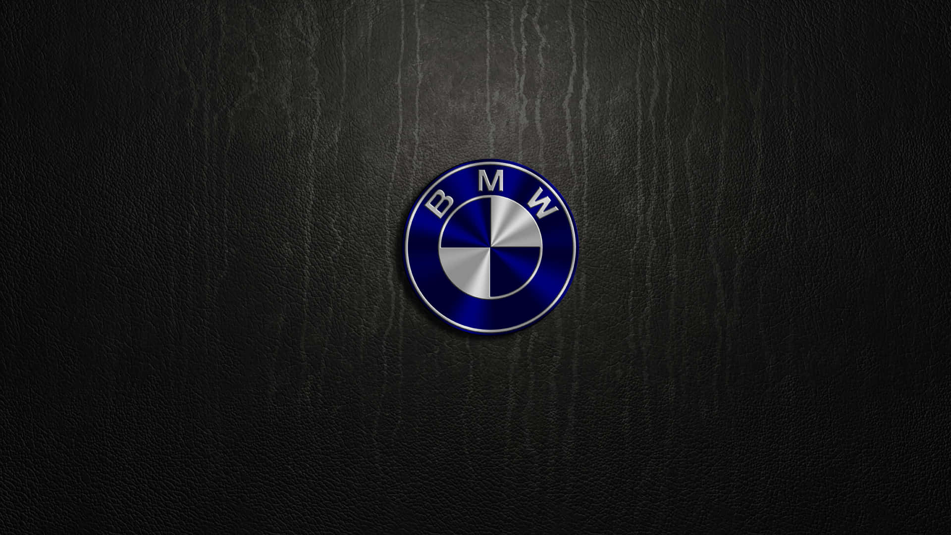 Bmw Logo 桌布 壁紙 — 一個帶有光澤的BMW標誌，置中於帶有細微垂直紋理的黑色皮革表面上。