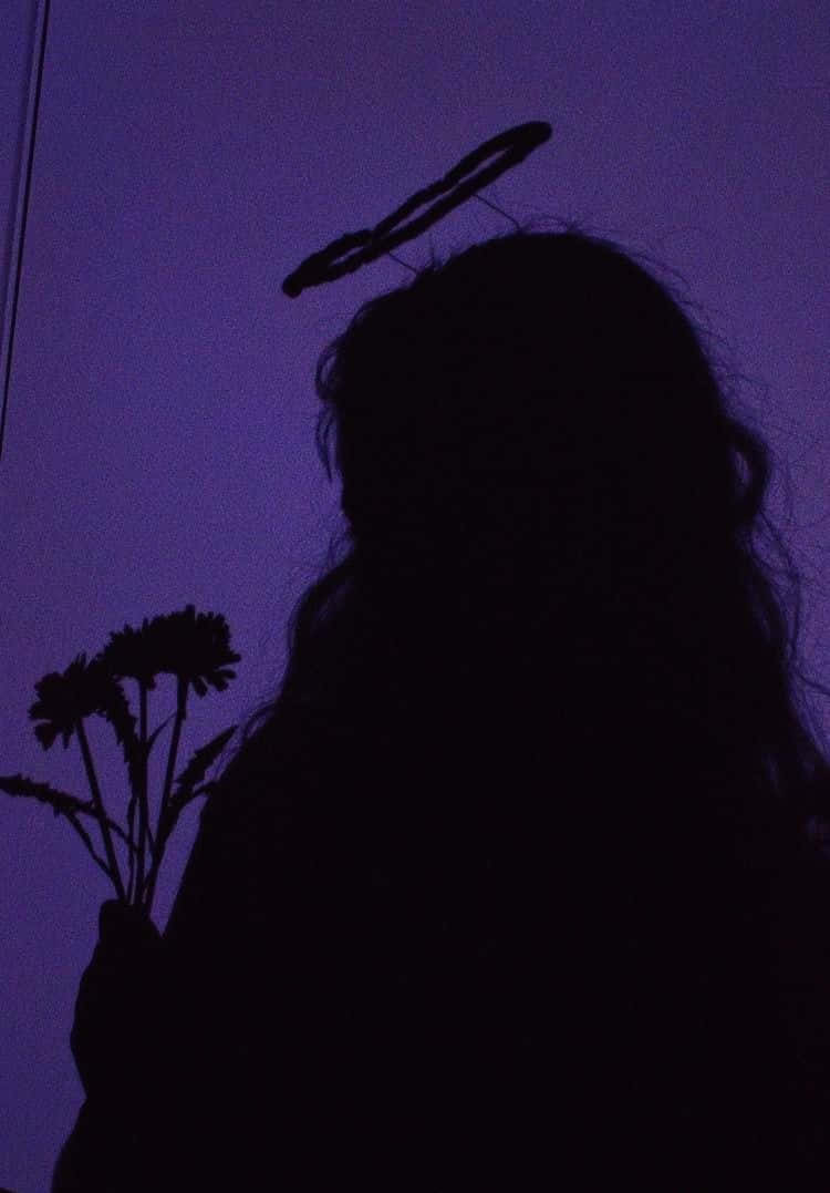 Violet Aesthetic 桌布 壁紙 — 一個帶有光環的人手持鮮花，背景是深紫色的暮色天空的剪影。
