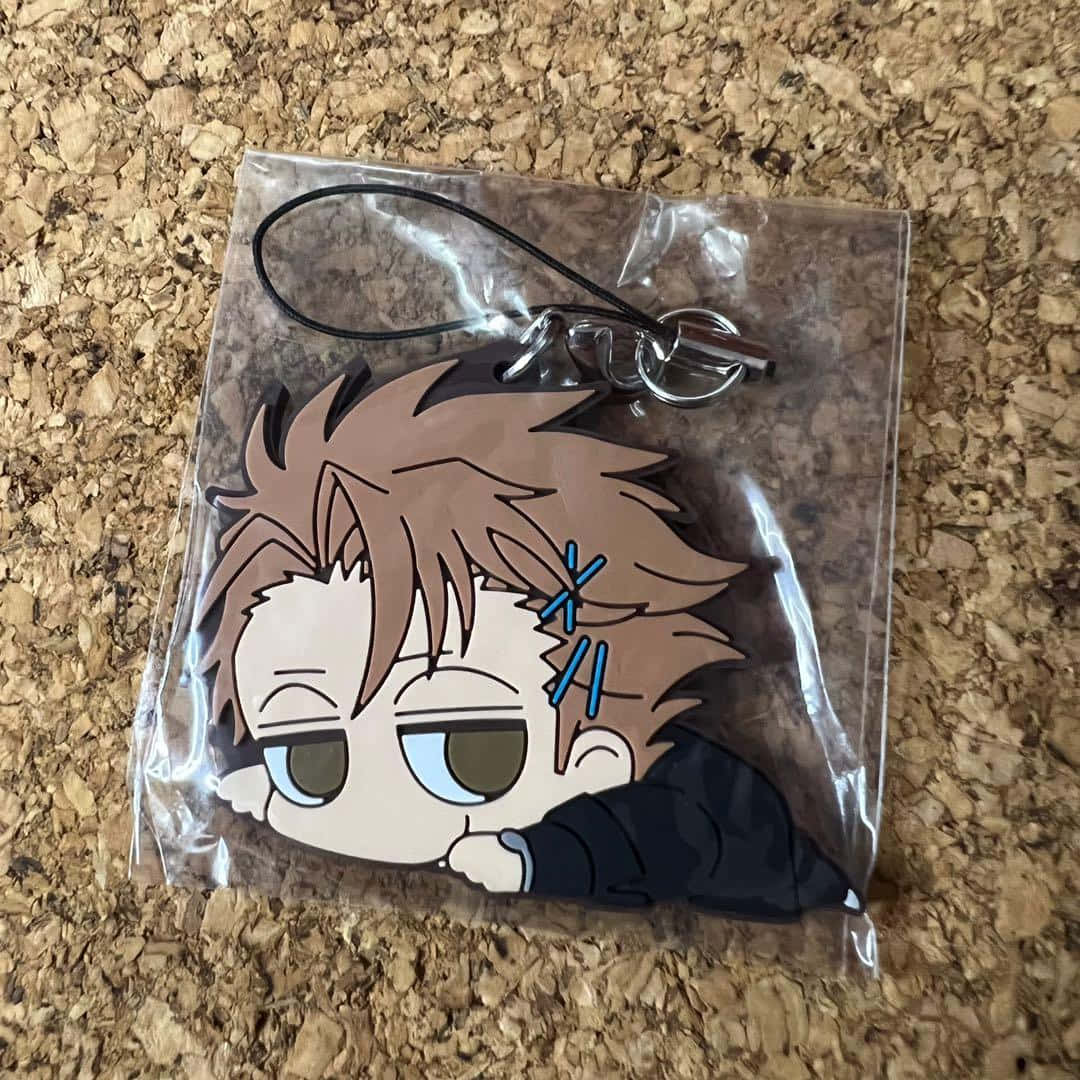 Shusei Kagari 桌布 壁紙 — 一個帶有凌亂棕色頭髮和疲倦眼睛的Q版動漫角色鑰匙圈，放在軟木表面上的透明塑膠中。