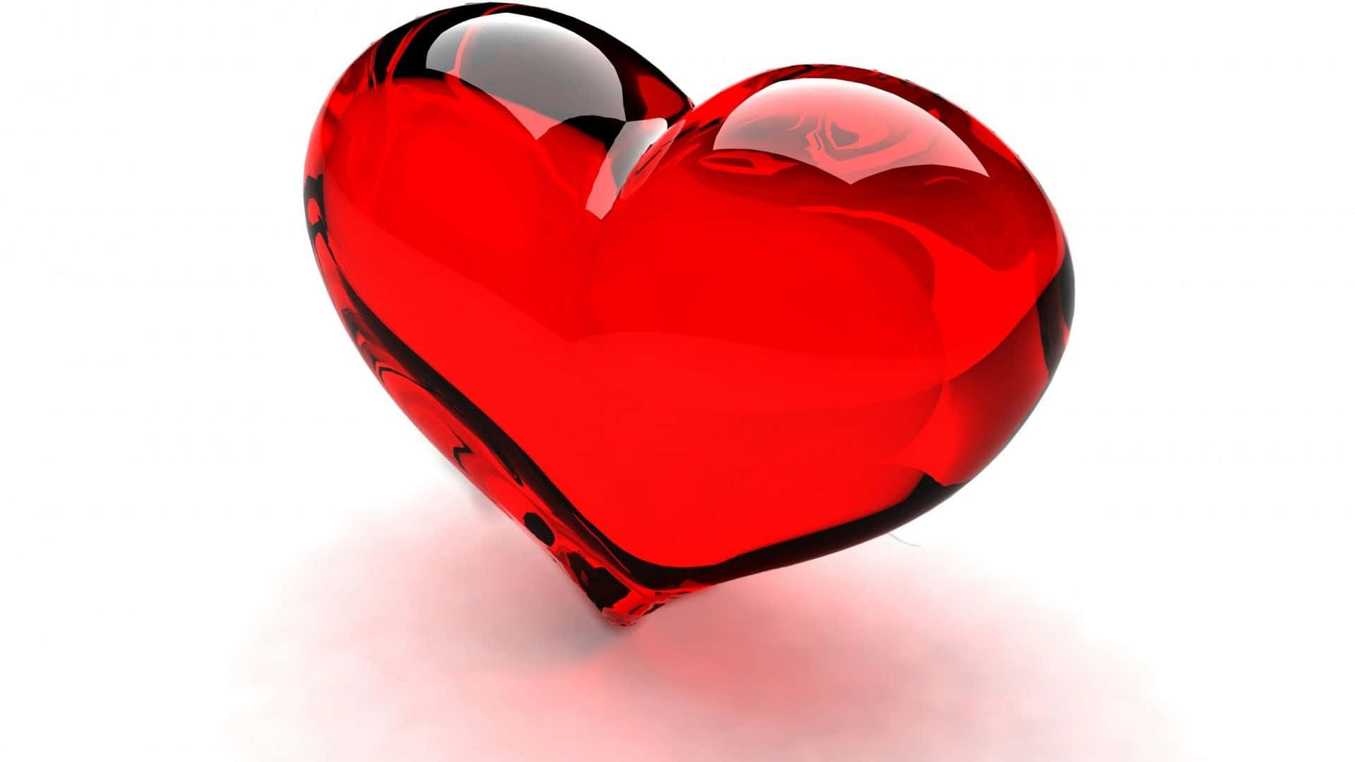 Red Heart 桌布 壁紙 — 一個帶有反射高光的亮面紅色心形玻璃物體，孤立地放置在白色表面上。