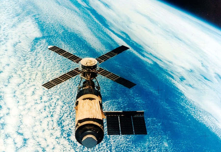 Space Colonization 桌布 壁紙 — 一個帶有太陽能板的太空站繞地球運行，下方顯示藍色海洋和白色雲層。