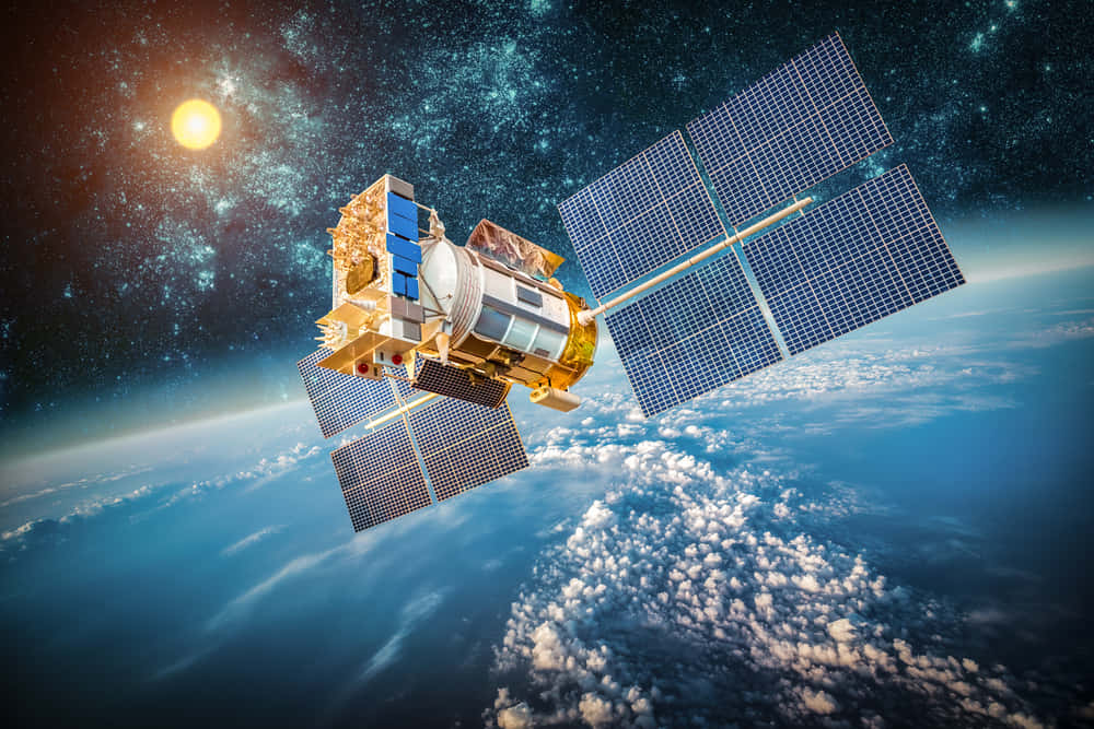 Satellite Technology 桌布 壁紙 — 一個帶有太陽能板的詳細衛星，在繁星點點的天空中繞地球運行，太陽明亮地照耀著。