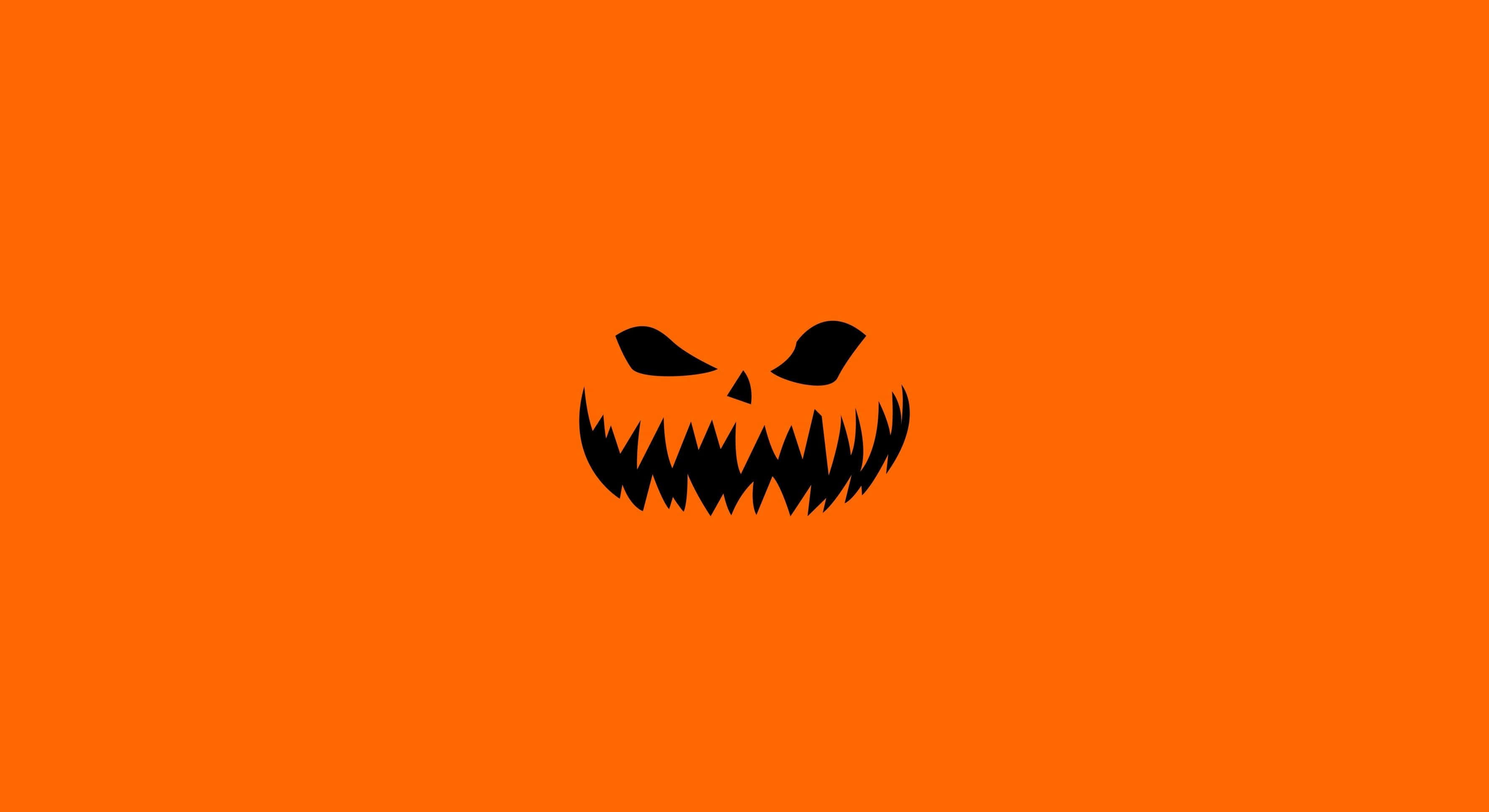 Orange Halloween 桌布 壁紙 — 一個帶有尖牙和狹窄眼睛的威脅性黑色傑克南瓜燈面孔，在純橙色背景上凝視。