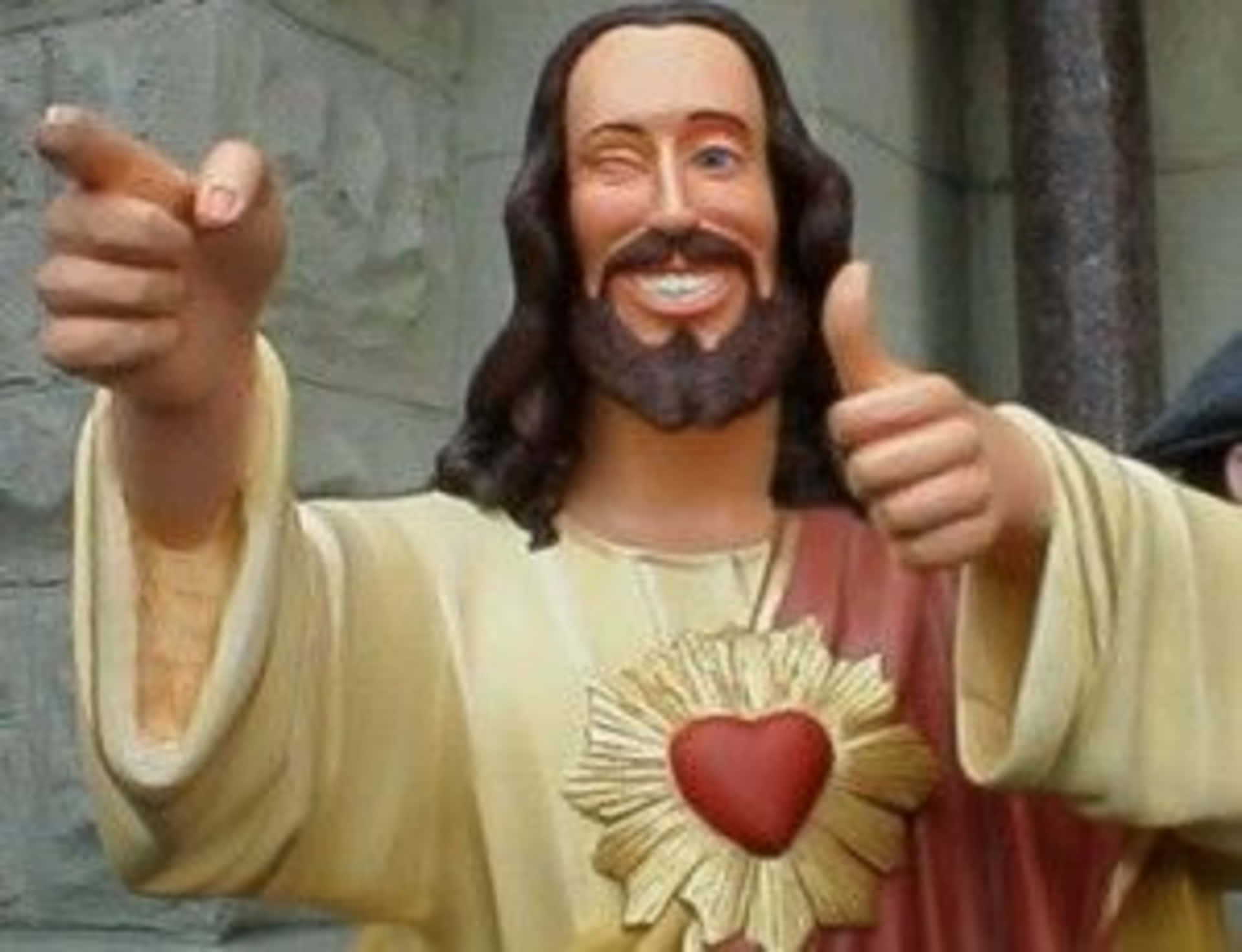 Cool Jesus 桌布 壁紙 — 一個帶有心形標誌的愉快耶穌雕像，向前指並豎起大拇指。
