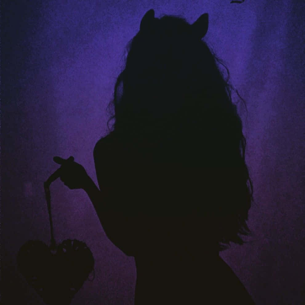 Violet Aesthetic 桌布 壁紙 — 一個帶有惡魔角的人物剪影，在陰鬱的紫色背景前拿著一個心形籃子。