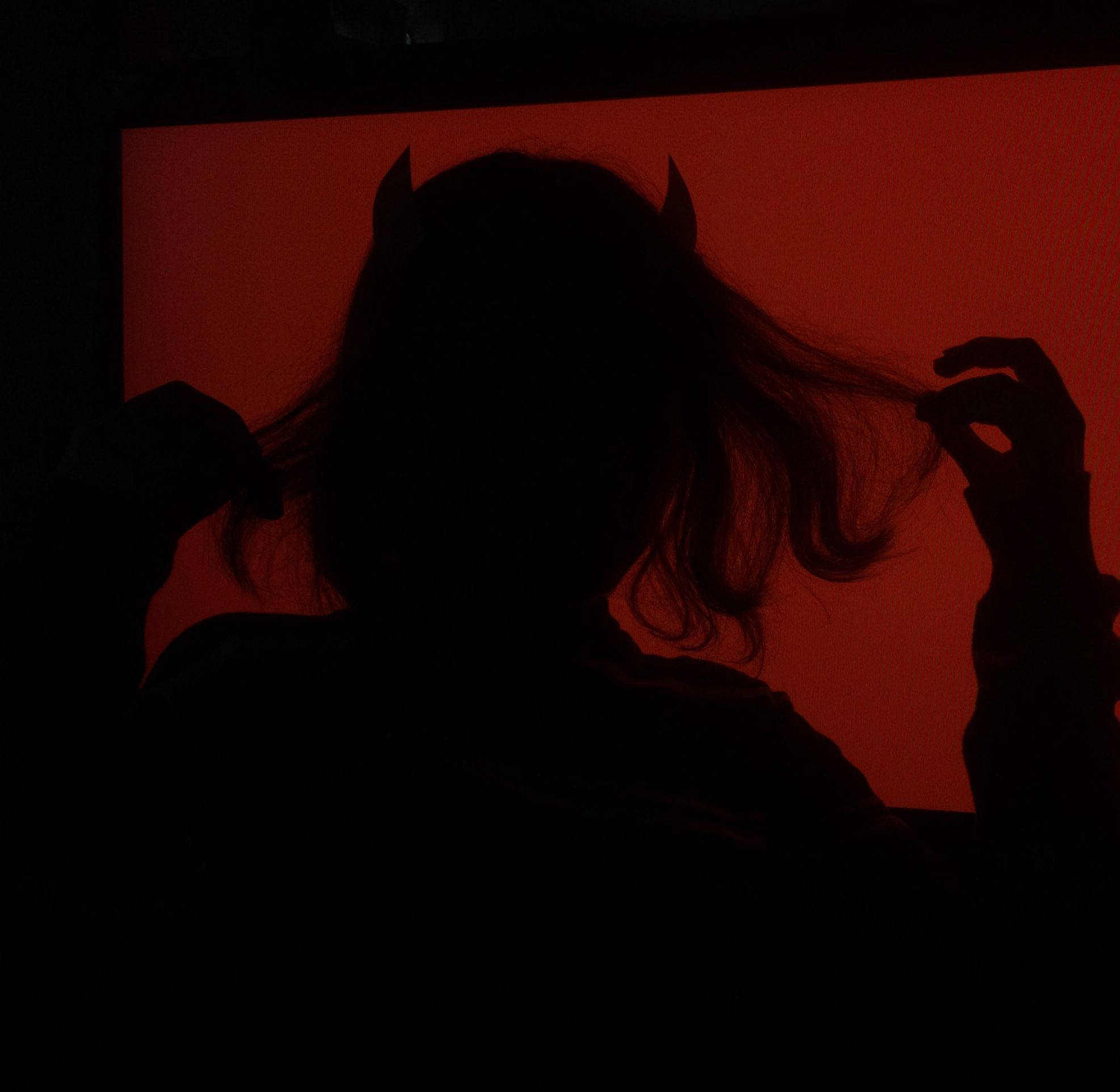Devil Horns 桌布 壁紙 — 一個帶有惡魔角的人的剪影，背景是發光的紅色，雙手輕輕觸碰頭髮。