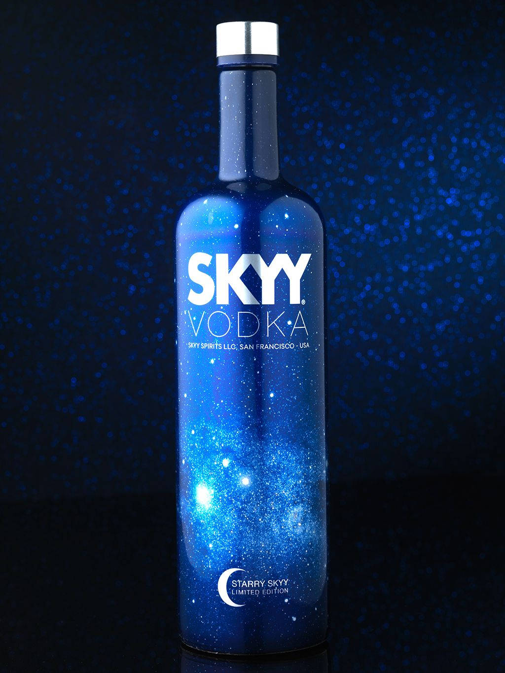 Drink 桌布 壁紙 — 一個帶有星空銀河設計的藍色伏特加酒瓶，立在深藍色斑點背景前。