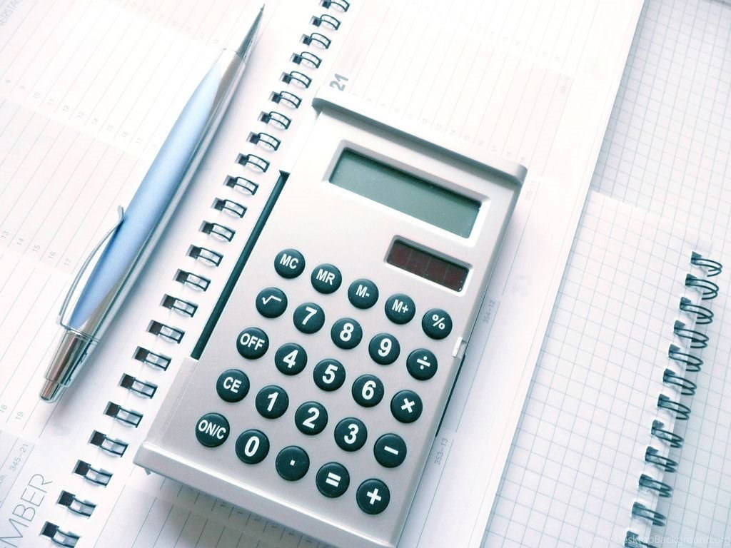 計算機 桌布 壁紙 — 一個帶有深綠色按鈕的銀色計算機放在方格紙上，旁邊有一支時尚的藍色筆。
