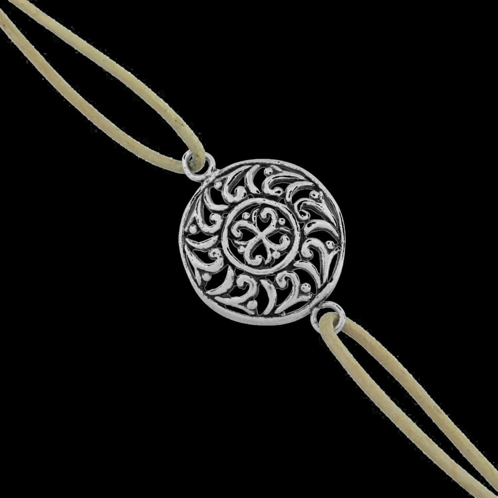 Bracelet 桌布 壁紙 — 一個帶有漩渦圖案的銀色鏤空吊墜，掛在一條淺米色繩子上，背景為純黑色。