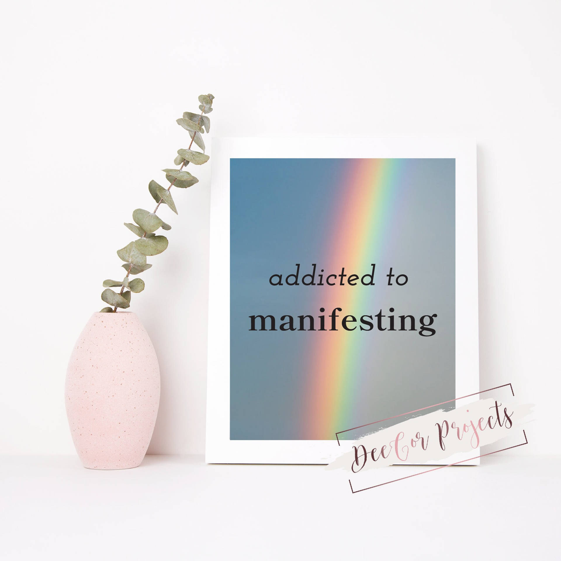 裱框印刷品，帶有彩虹和文字「addicted to manifesting」，旁邊是一個粉紅色花瓶，插著尤加利葉。 — 顯現 GIF 壁紙