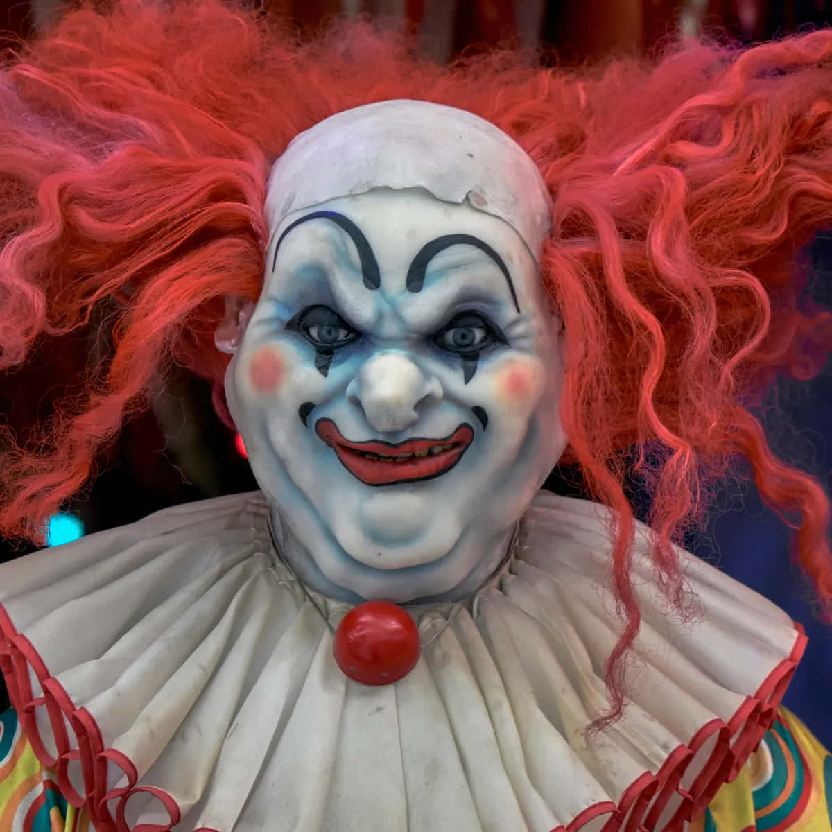 Creepy Clown 桌布 壁紙 — 一個帶有狂野紅髮和塗著臉、露出邪惡笑容的威脅性小丑的特寫。