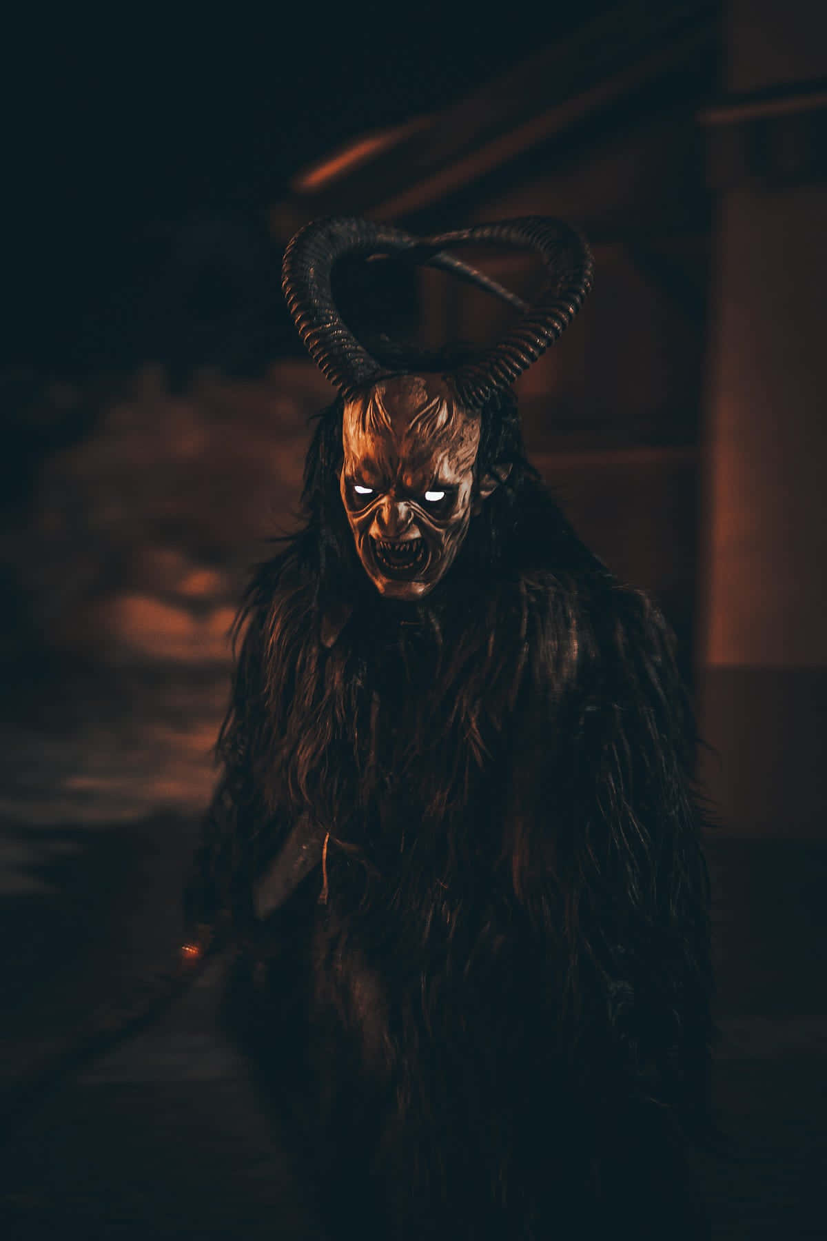 惡魔動圖 桌布 壁紙 — 一個帶有發光眼睛和毛皮的可怕有角惡魔，站在昏暗、詭異的夜晚環境中。