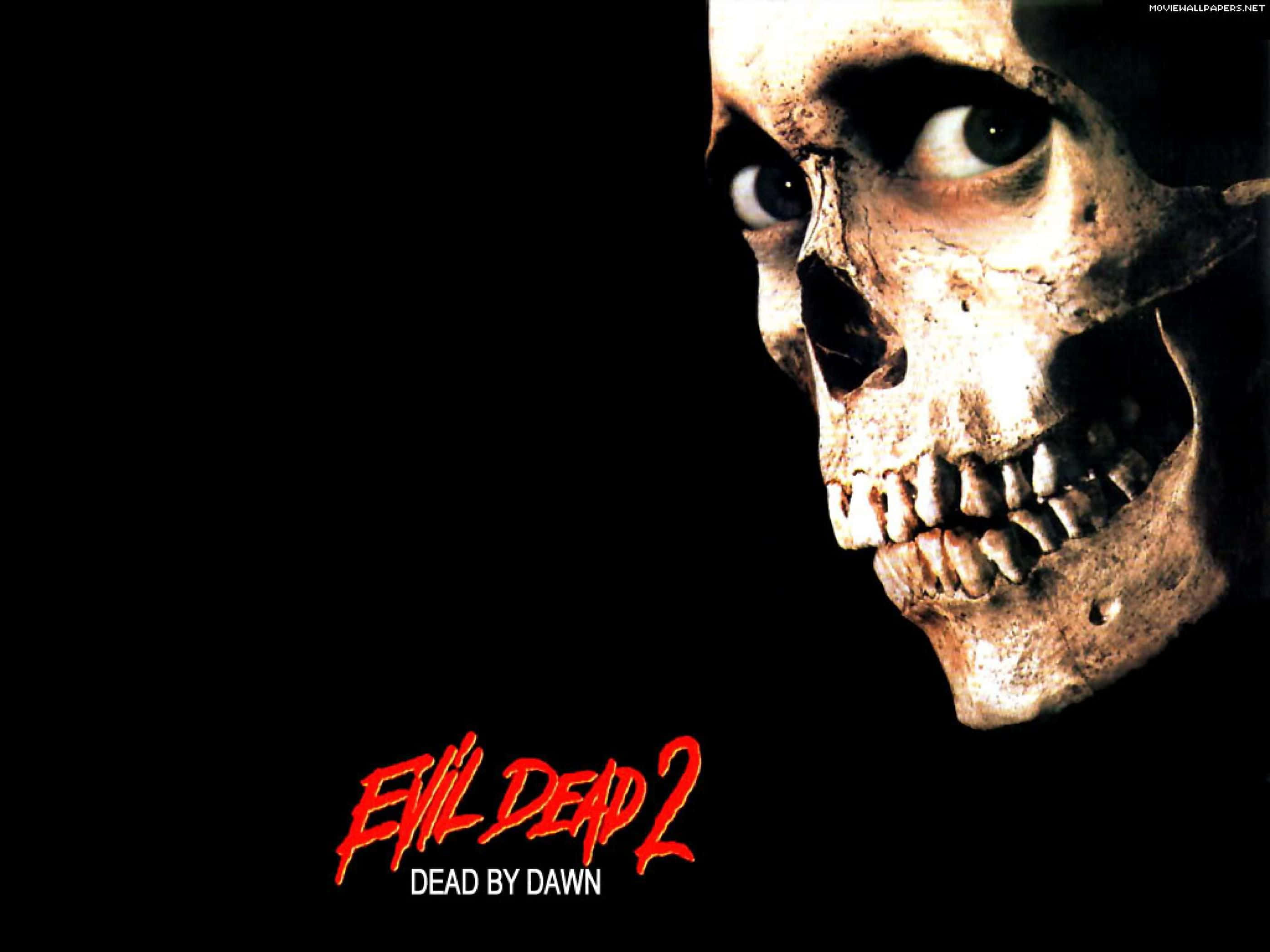 Evil Skull 桌布 壁紙 — 一個帶有發光眼睛的可怕頭骨從黑暗中凝視，背景為黑色，帶有紅色電影標題文字。