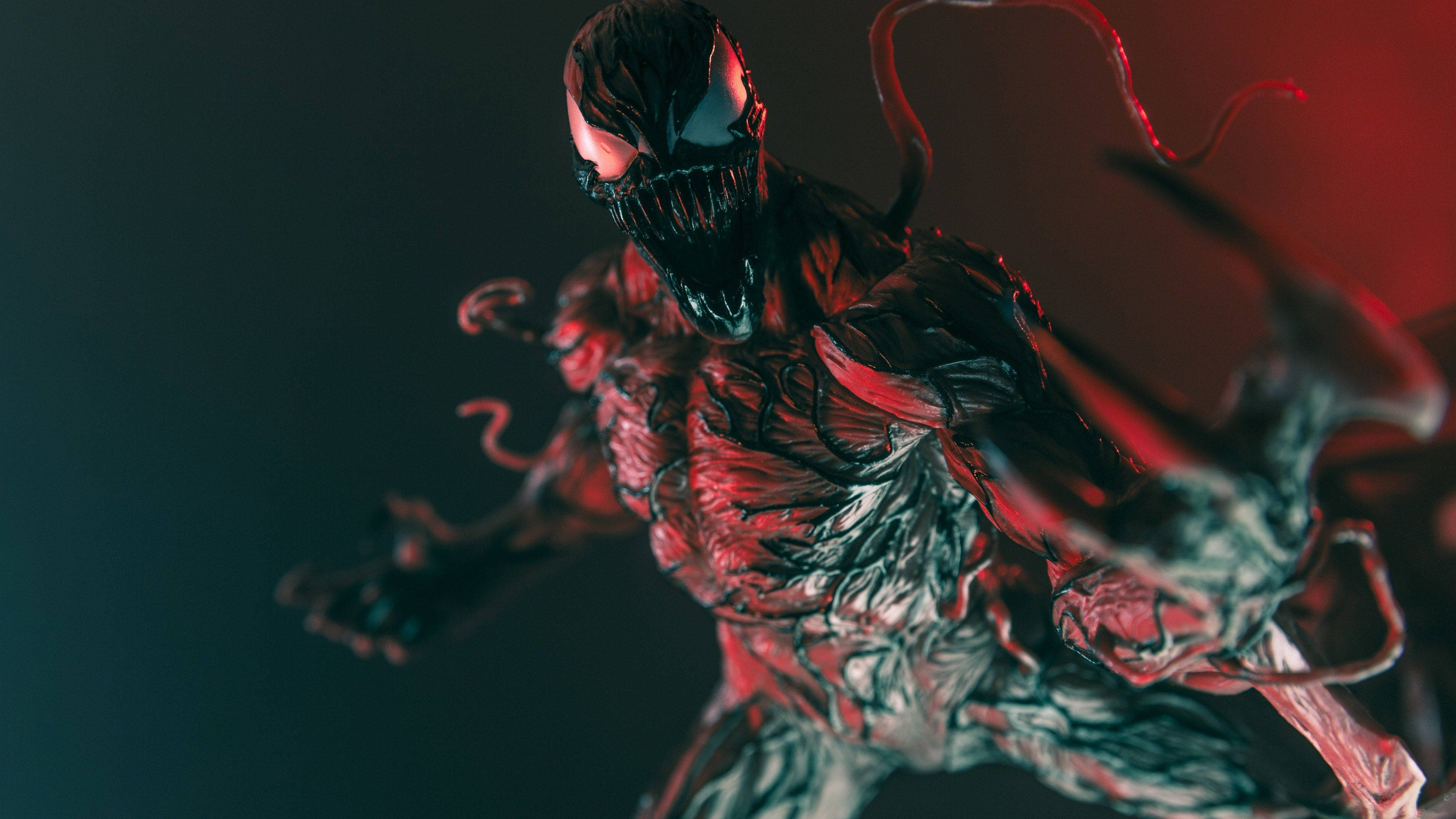 carnage 4K 桌布 壁紙 — 一個帶有發光紅眼和觸手的威脅性毒魔形象，在深色漸變背景前向前猛撲。