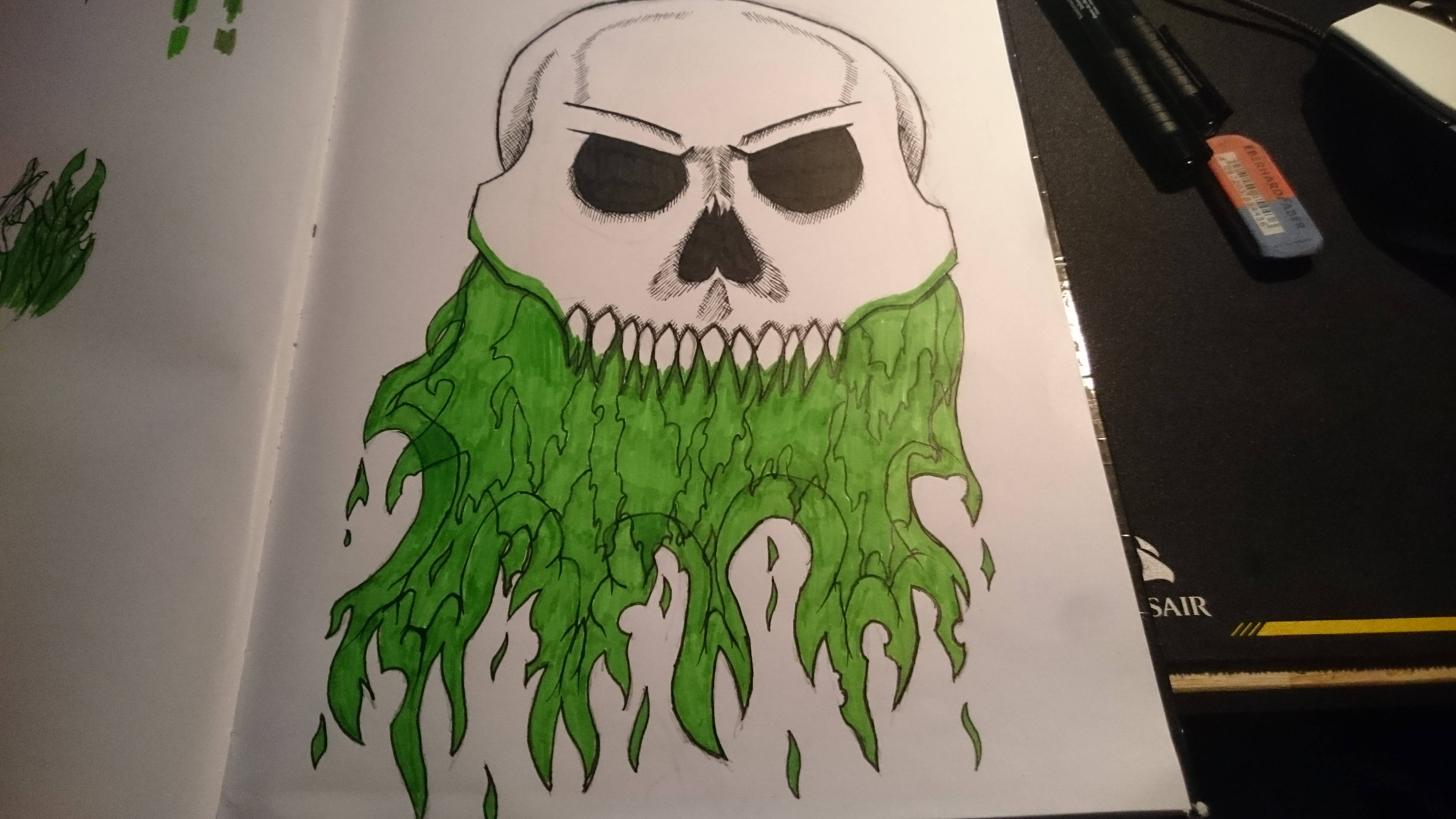 Green Fire Skull 桌布 壁紙 — 一個帶有發光綠色鬍鬚的可怕頭骨，畫在書桌上的素描本中，桌上還有美術用品。