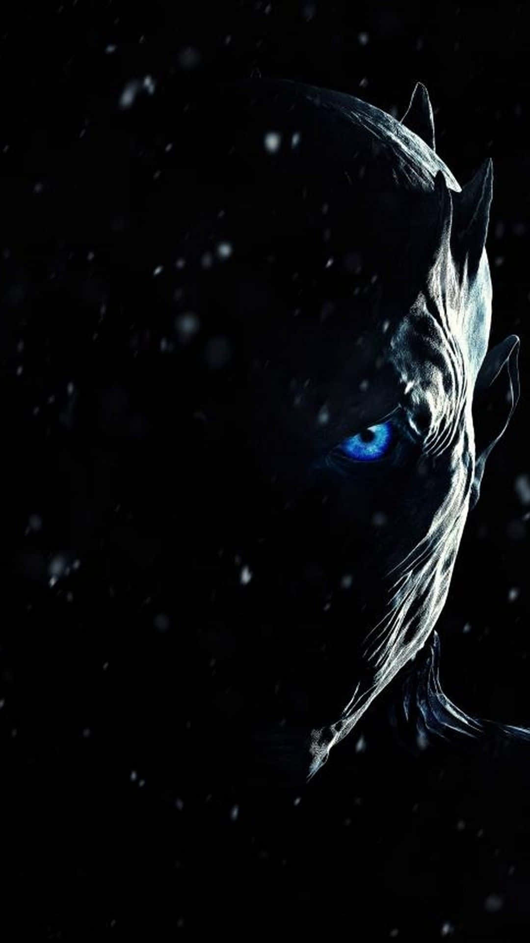 Game Of Thrones iPhone 桌布 壁紙 — 一個帶有發光藍眼睛的威脅性白色行者從黑暗中出現，雪花在其冰冷的臉龐周圍飄舞。