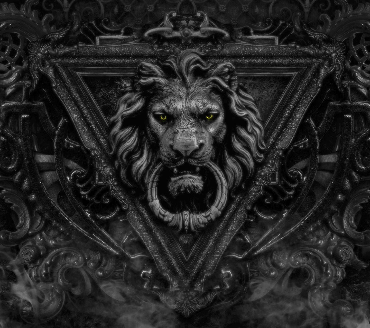 Lion Head 桌布 壁紙 — 一個帶有發光黃色眼睛的威嚇獅子頭從華麗的深色金屬工藝中浮現，背景是煙霧彌漫的黑色。
