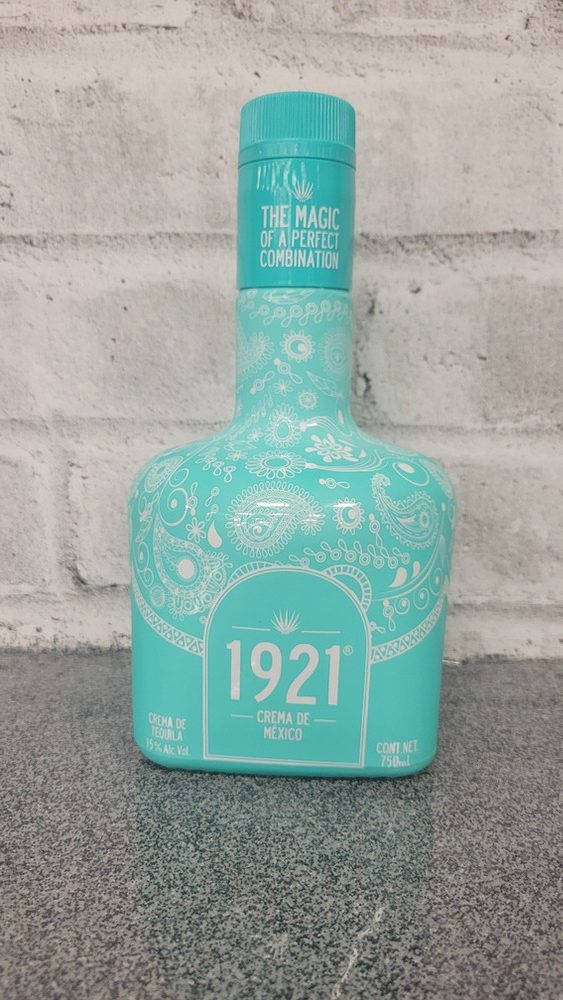 drinks 桌布 壁紙 — 一個帶有白色佩斯利圖案的土耳其藍色1921 Crema de Mexico龍舌蘭酒瓶，放在灰色檯面上，背景是白色磚牆。