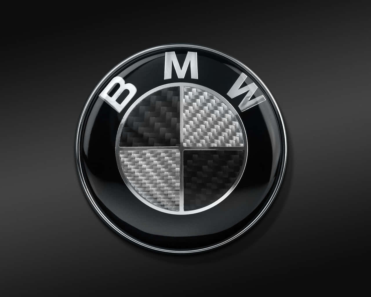 Bmw Logo 桌布 壁紙 — 一個帶有碳纖維四分之一圓的光澤BMW標誌，在深色漸變背景上閃耀。