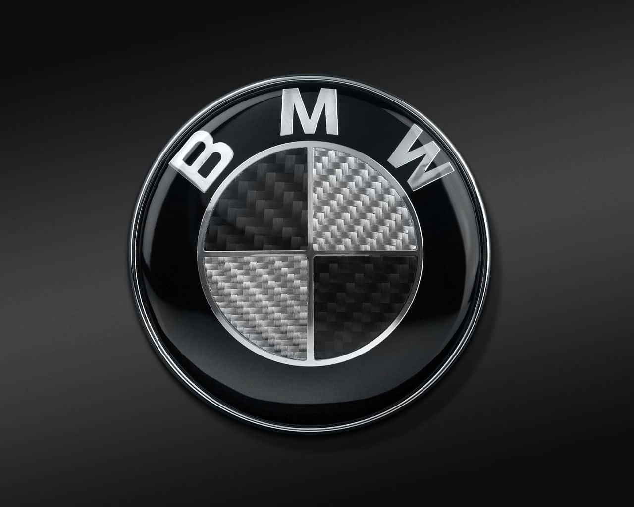 Bmw Logo 桌布 壁紙 — 一個帶有碳纖維紋理四分之一部分的光面BMW標誌，置於深色漸變背景上。