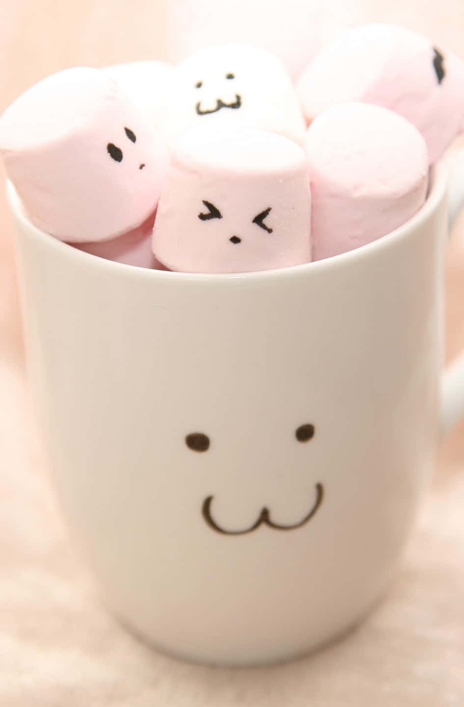 帶有笑臉的白色馬克杯，裝滿了畫有臉的粉紅色棉花糖。 — Squishmallows 壁紙