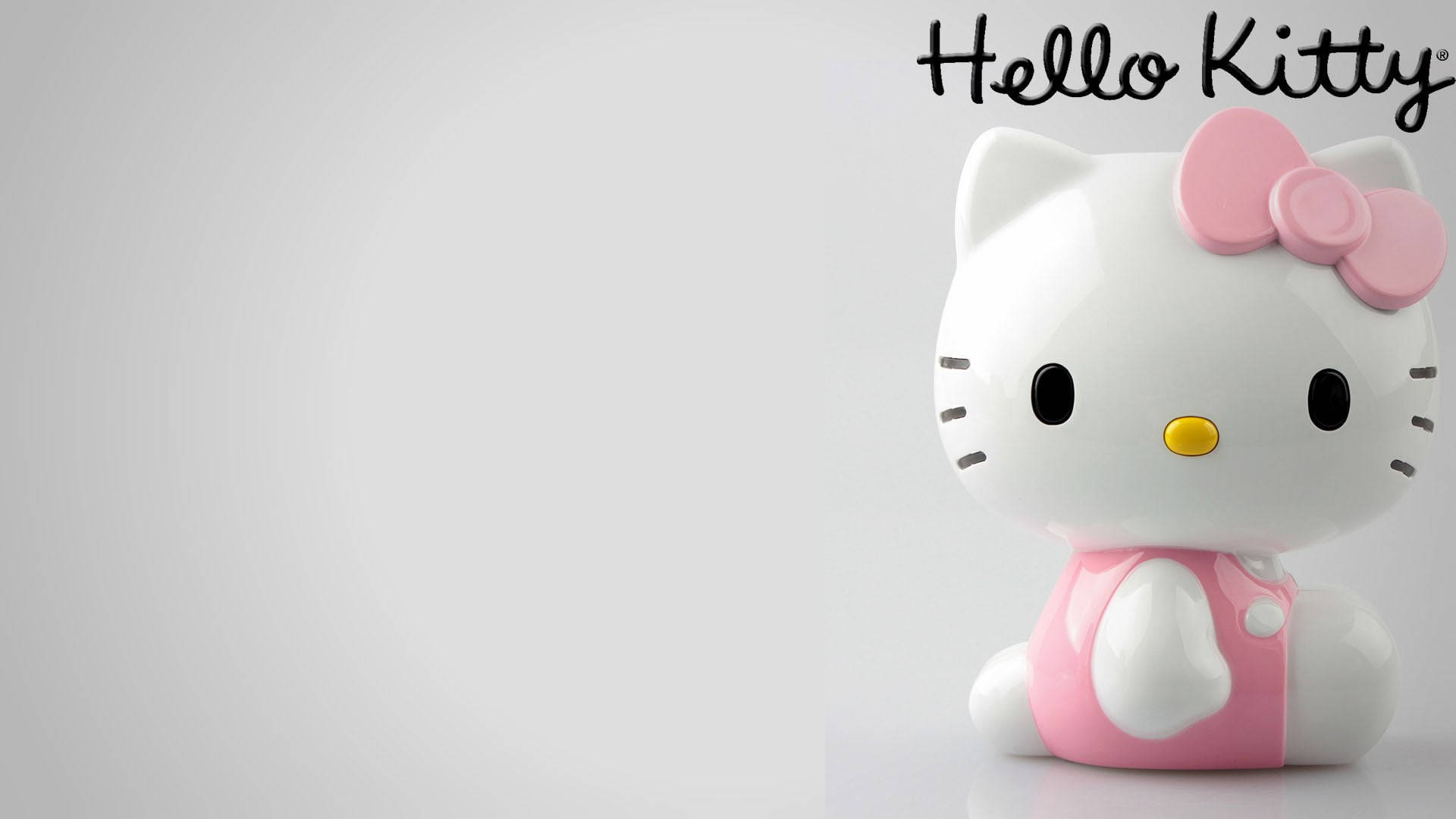 Hello 桌布 壁紙 — 一個帶有粉紅色蝴蝶結和連衣裙的光澤白色Hello Kitty公仔，坐在純淺灰色背景前。
