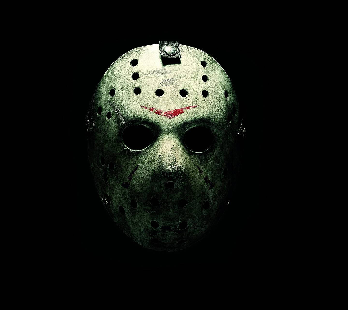 jason 桌布 壁紙 — 一個帶有紅色劃痕的風化綠色曲棍球面具在漆黑背景中發光。