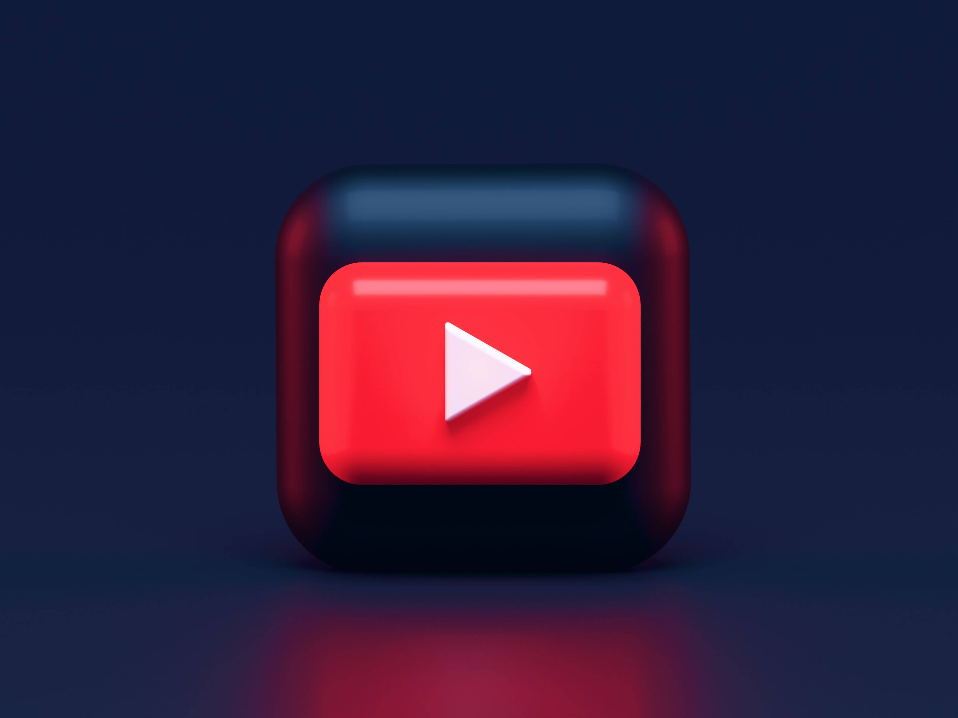 動態桌面 桌布 壁紙 — 一個帶有紅色和黑色漸層的光澤3D渲染YouTube播放按鈕圖示，背景為深藍色。