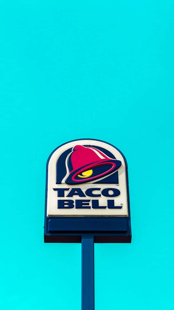 塔可鐘 桌布 壁紙 — 一個帶有紅色鈴鐺標誌的Taco Bell招牌，矗立在充滿活力的藍綠色背景前。